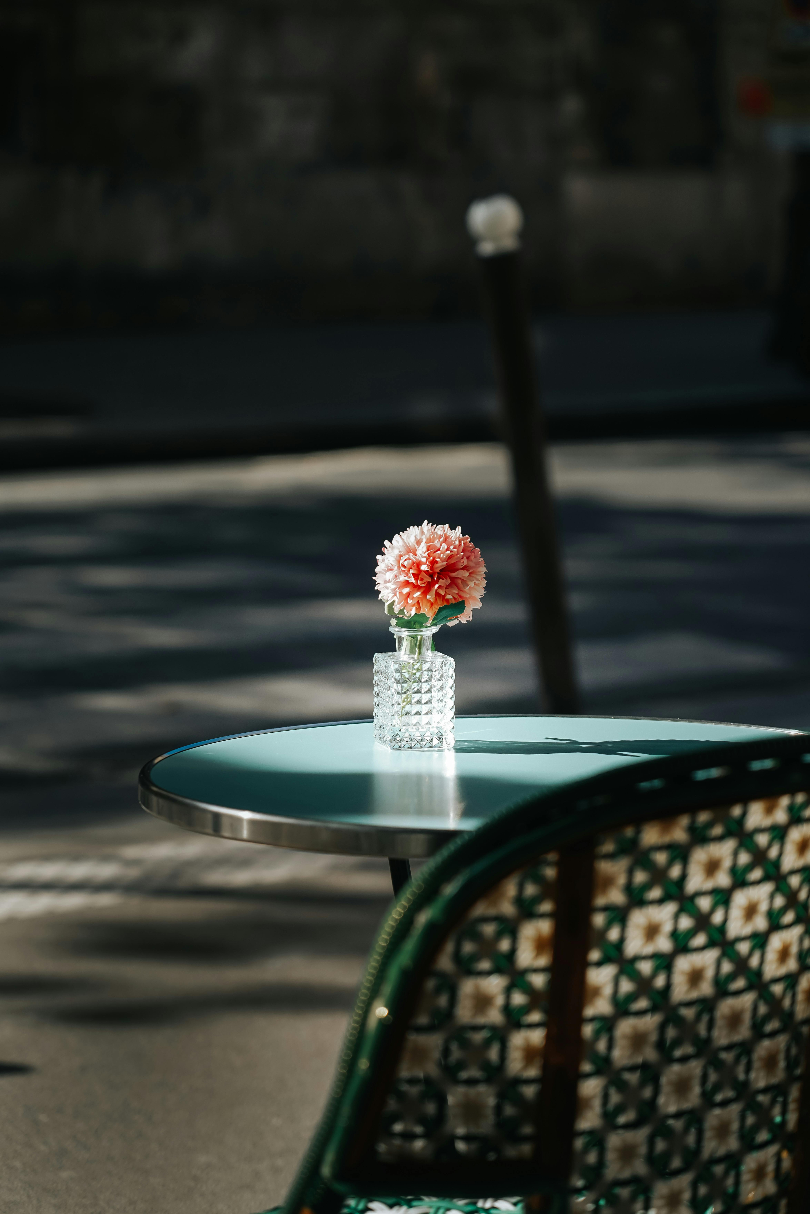 Flower in a glass vase on a small cafe table.