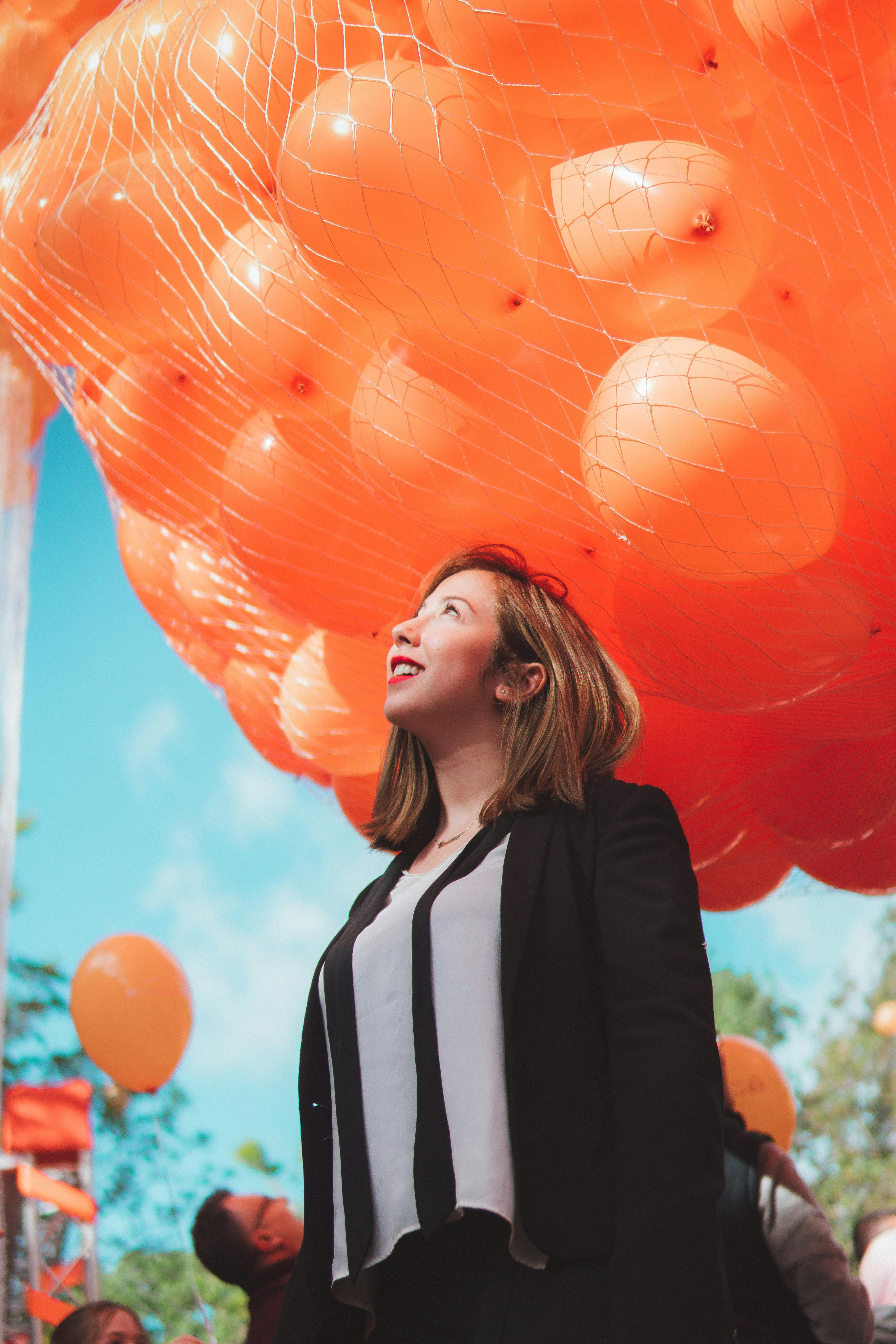 Woman with net full of orange balloons above her.